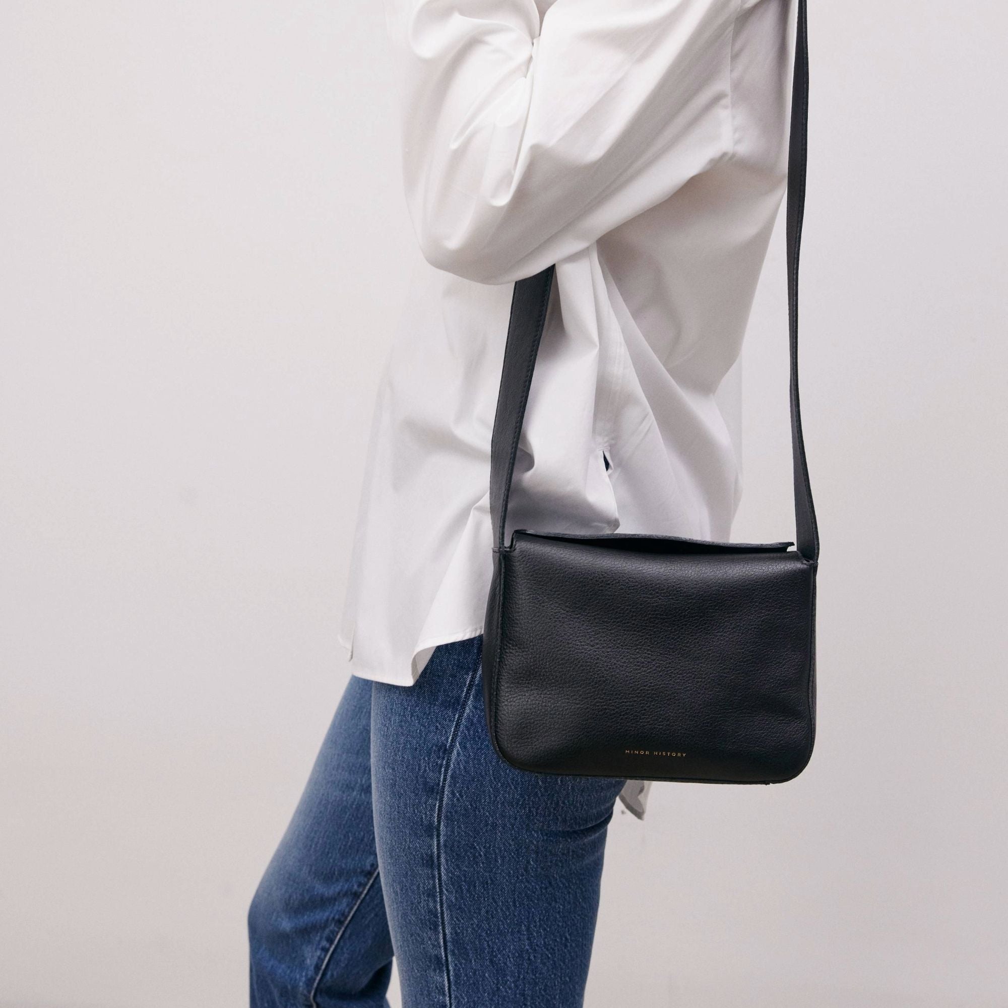 Little Frame crossbody bag in black full-grain leather, front view showcasing its sculpted shape, minimalist women's handbag - Black