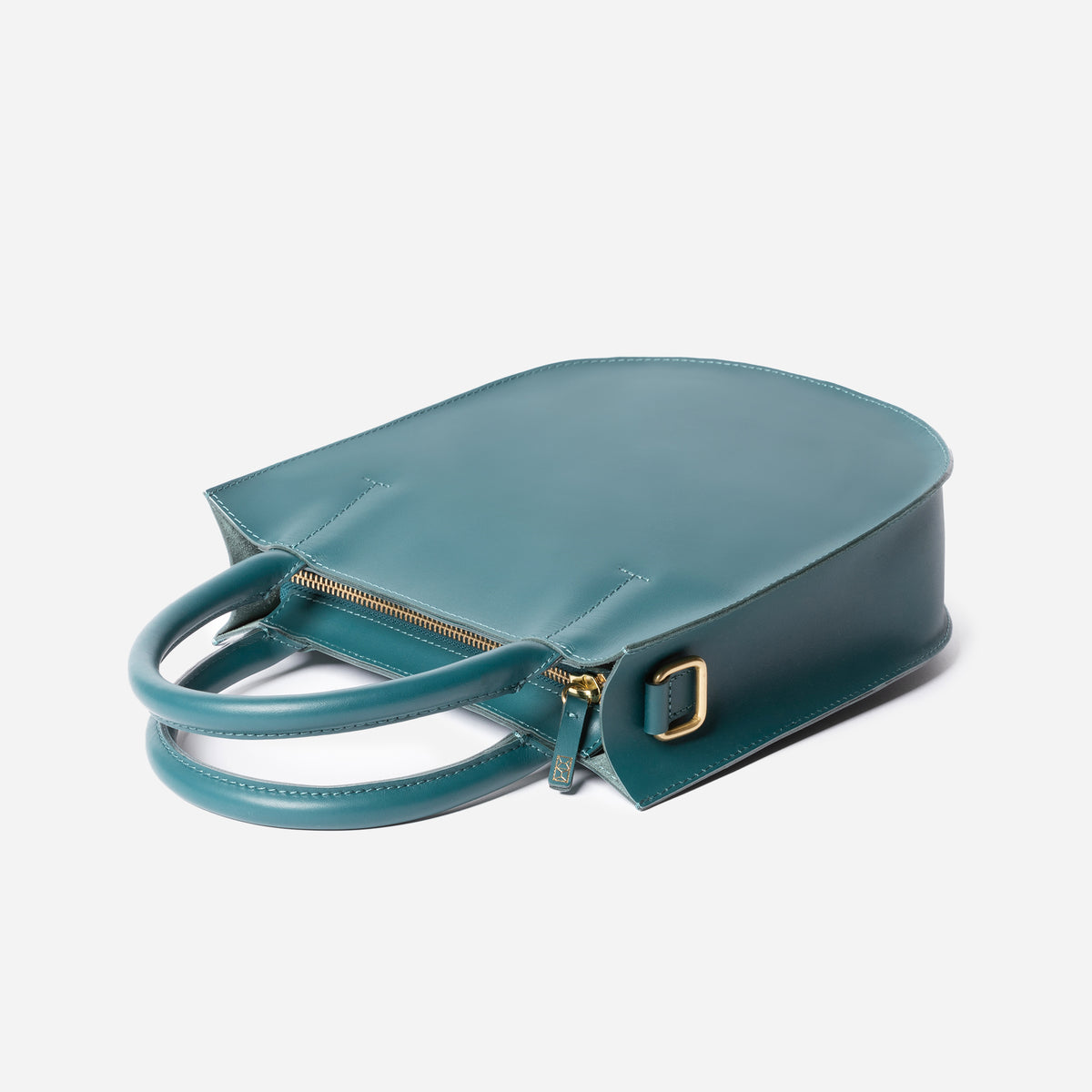 Teal handbag with gold zipper and buckle on a light gray background - Dawn