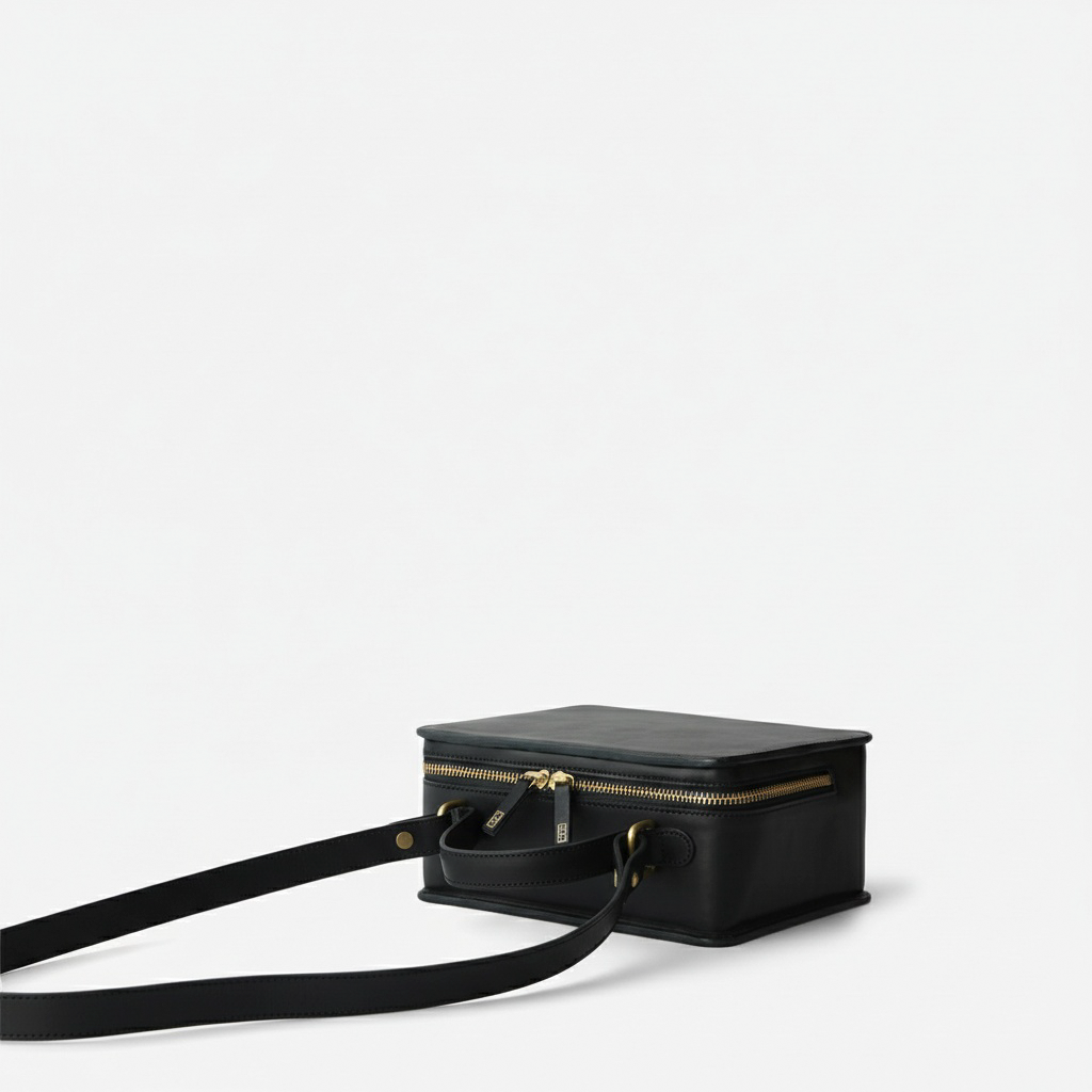 Black handbag with gold zipper on a light gray background - Black
