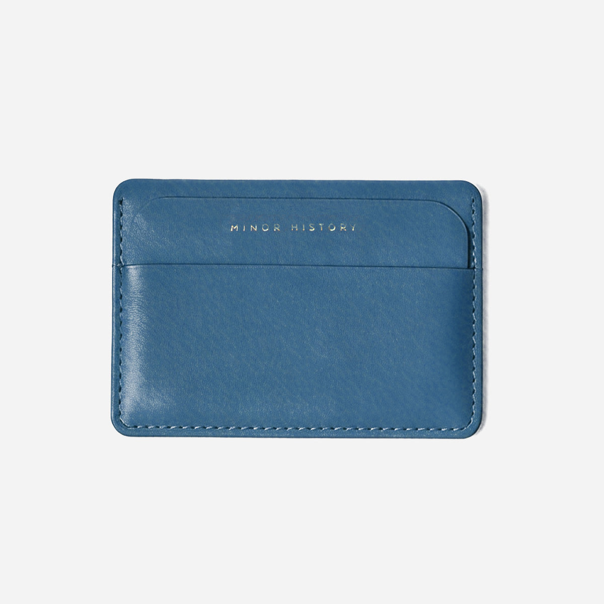 Blue cardholder with 'Minor History' branding on a light gray background - Chambray