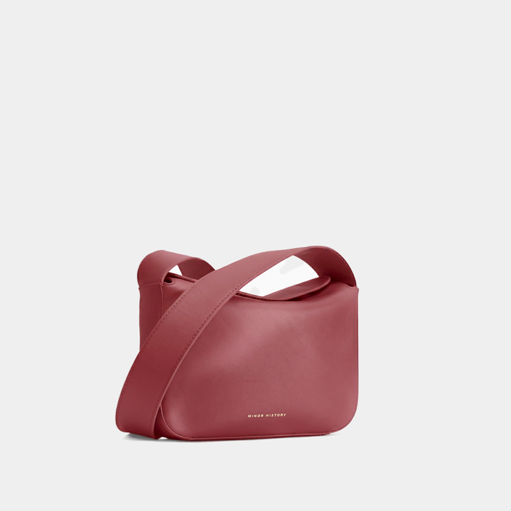 Red handbag with a visible brand name on a light gray background - Cherry Cola