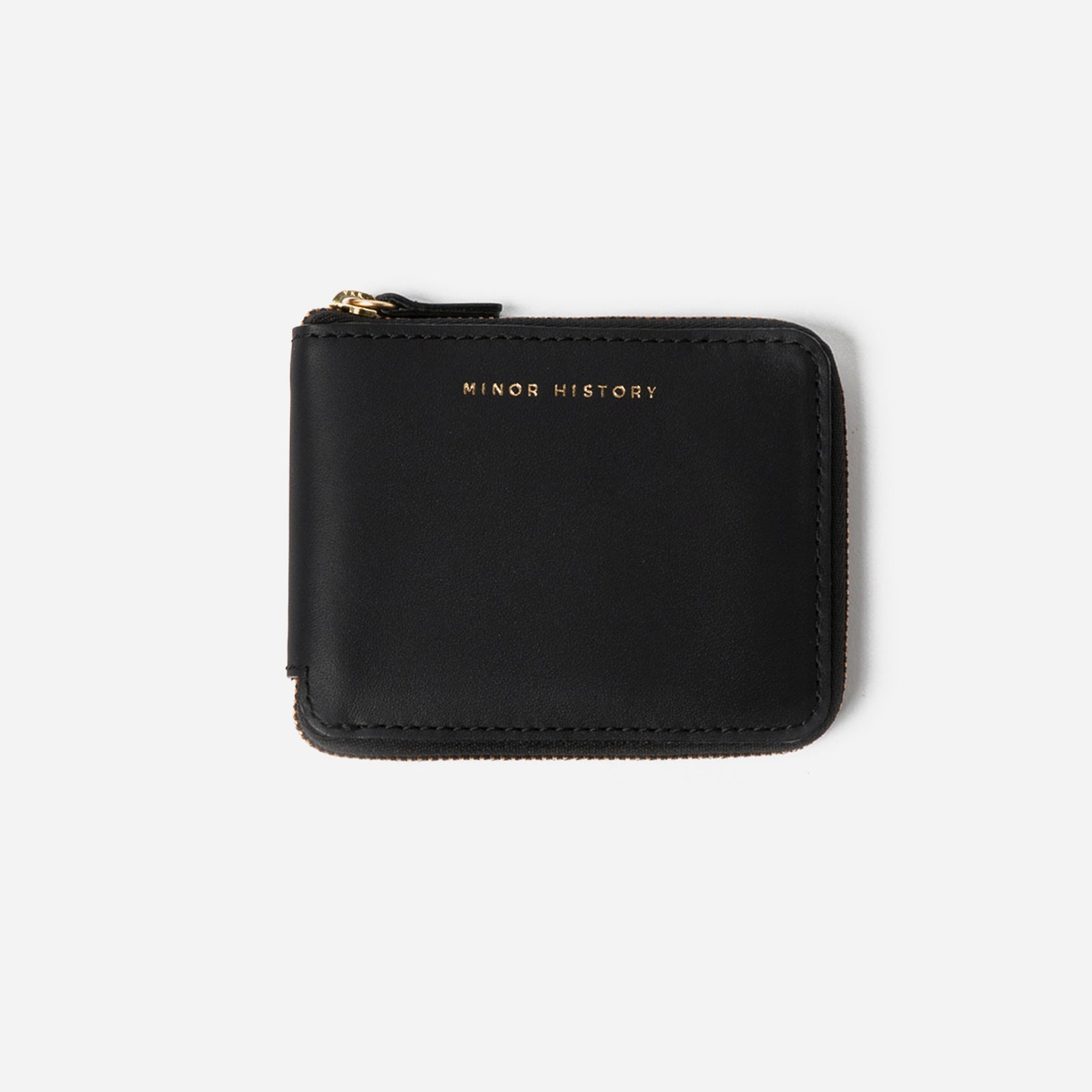 Brown wallet with 'Minor History' branding on a pink fabric background - Saddle