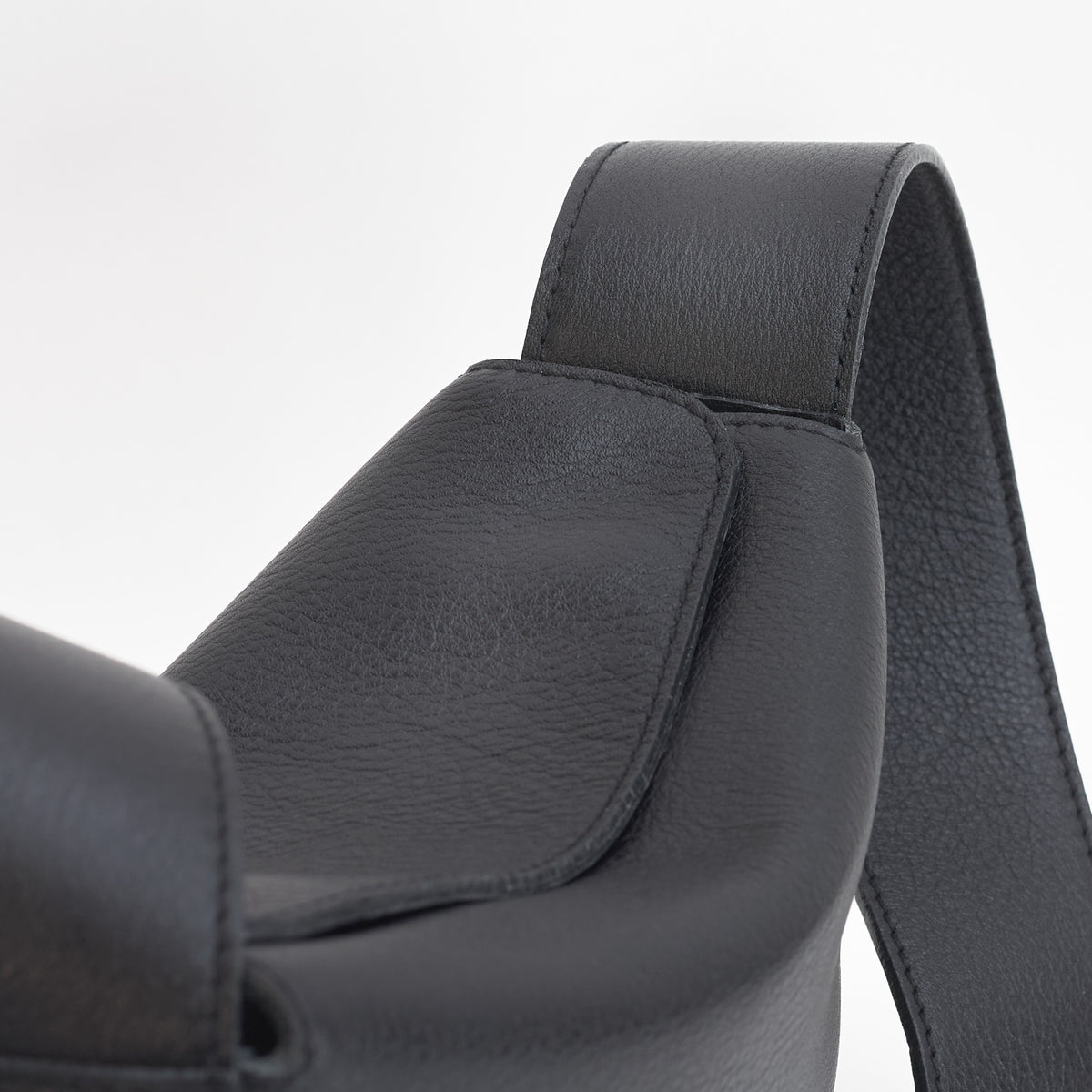 Little Frame crossbody bag in black full-grain leather, close-up of strap attachment and smooth texture, minimalist women's handbag - Black