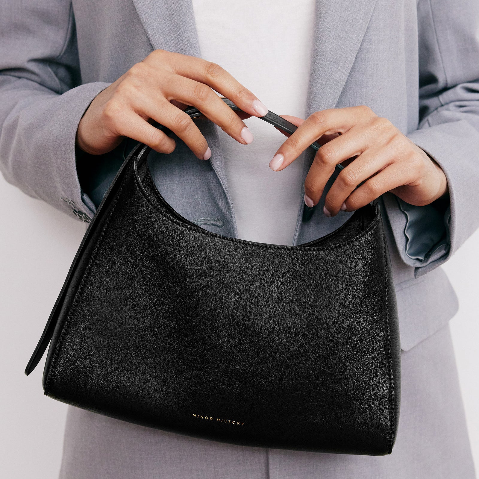 Overtime Tote Bag in black leather shown on minimalist background - Black