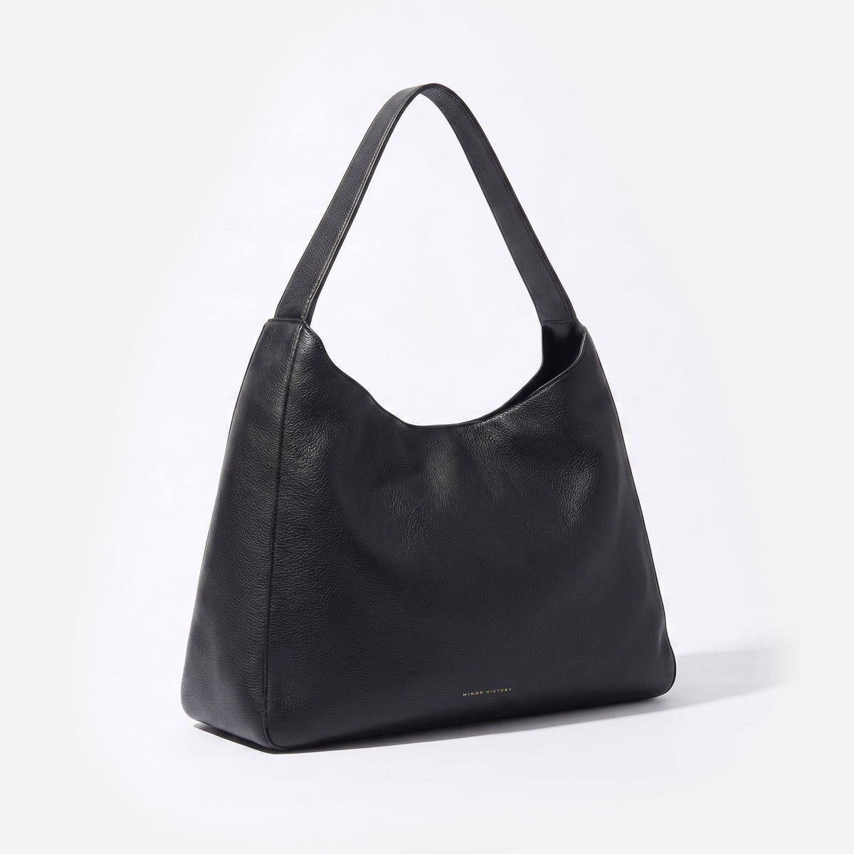 A black pebbled leather hobo shoulder bag with a single strap, photographed from a three-quarter angle on a clean white background. -Black