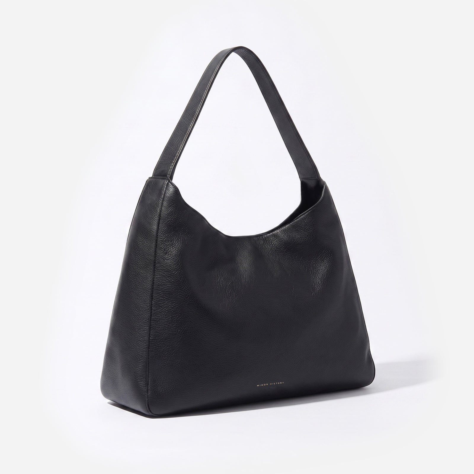A black pebbled leather hobo shoulder bag with a single strap, photographed from a three-quarter angle on a clean white background. -Black