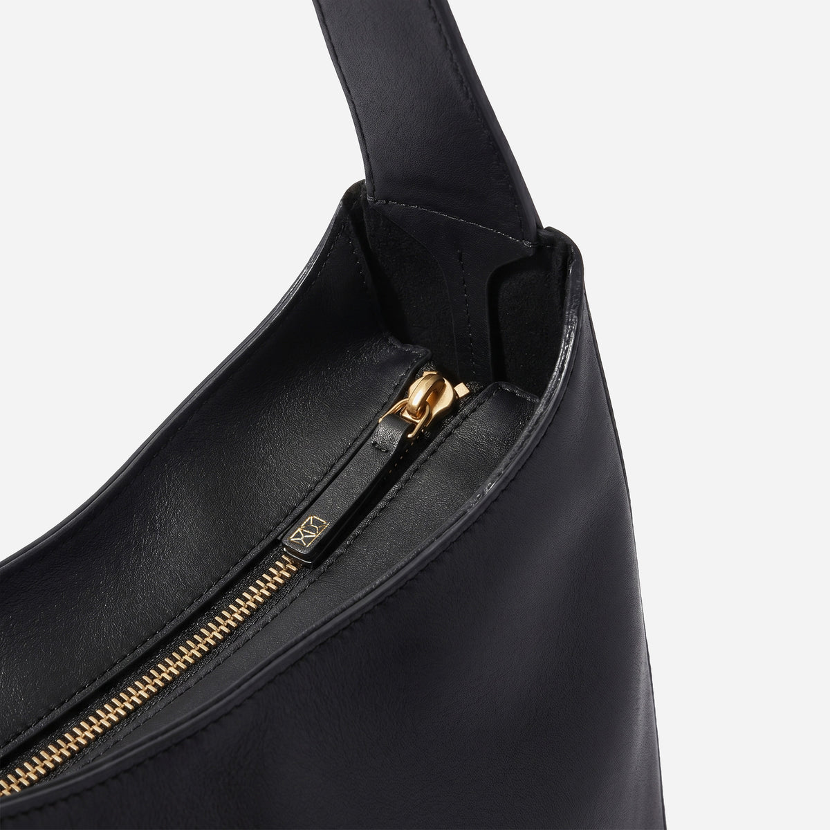 Black handbag with gold zipper on a light gray background - Black