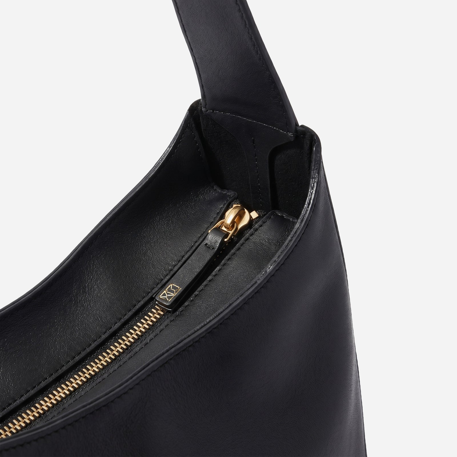 Black handbag with gold zipper on a light gray background - Black
