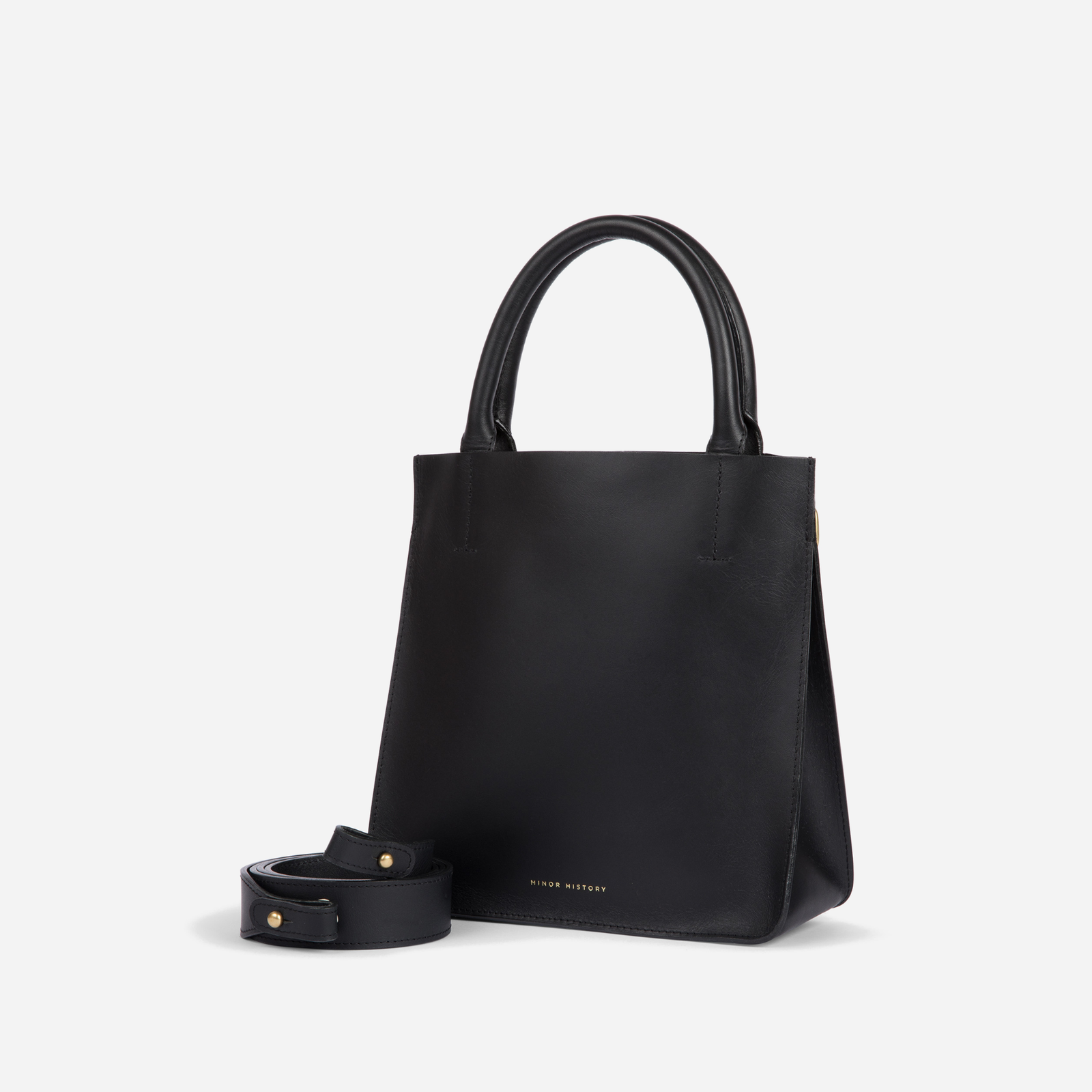 A silver crossbody leather bag with a removable strap and brass hardware, displayed against a plain background. - Sterling