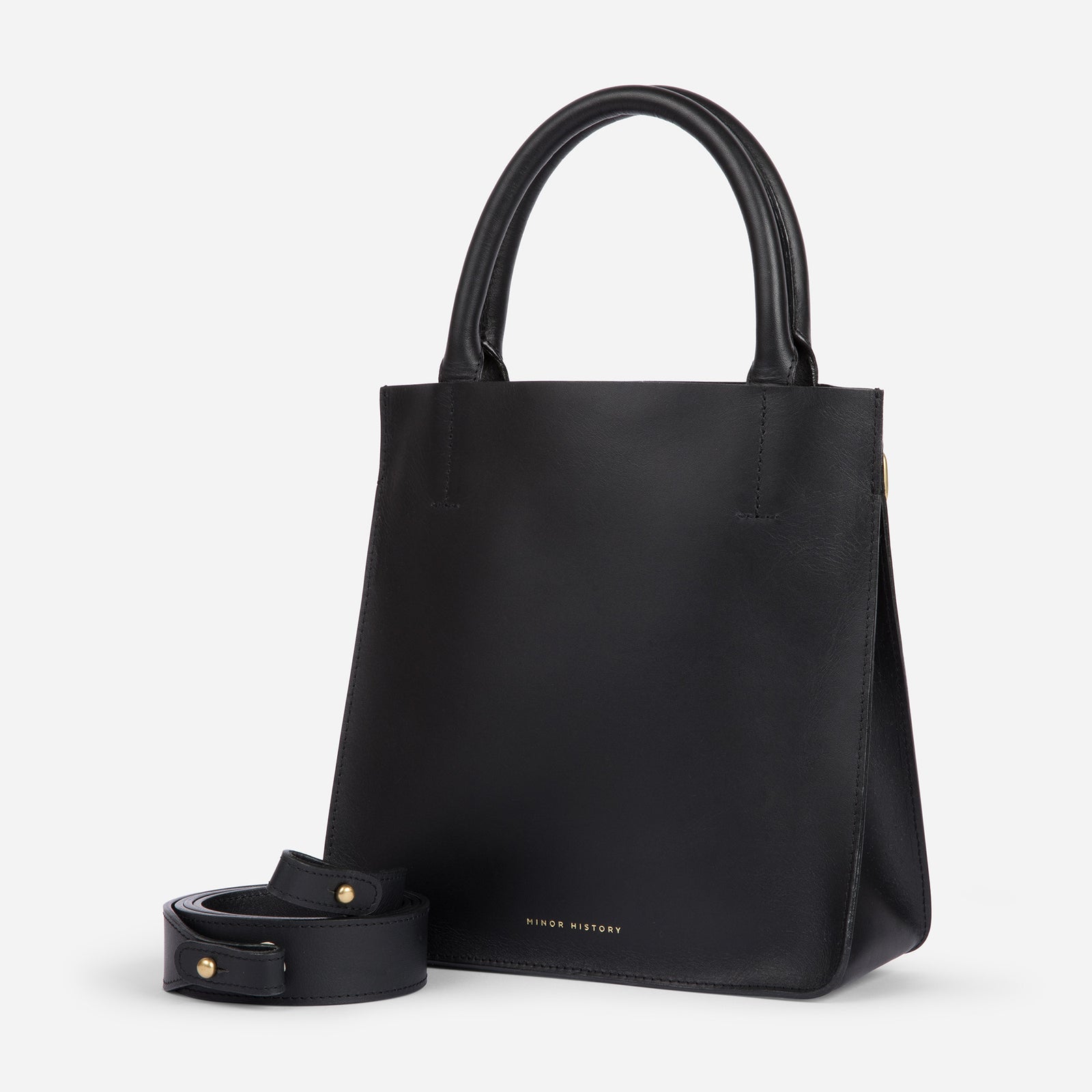 A silver crossbody leather bag with a removable strap and brass hardware, displayed against a plain background. - Sterling