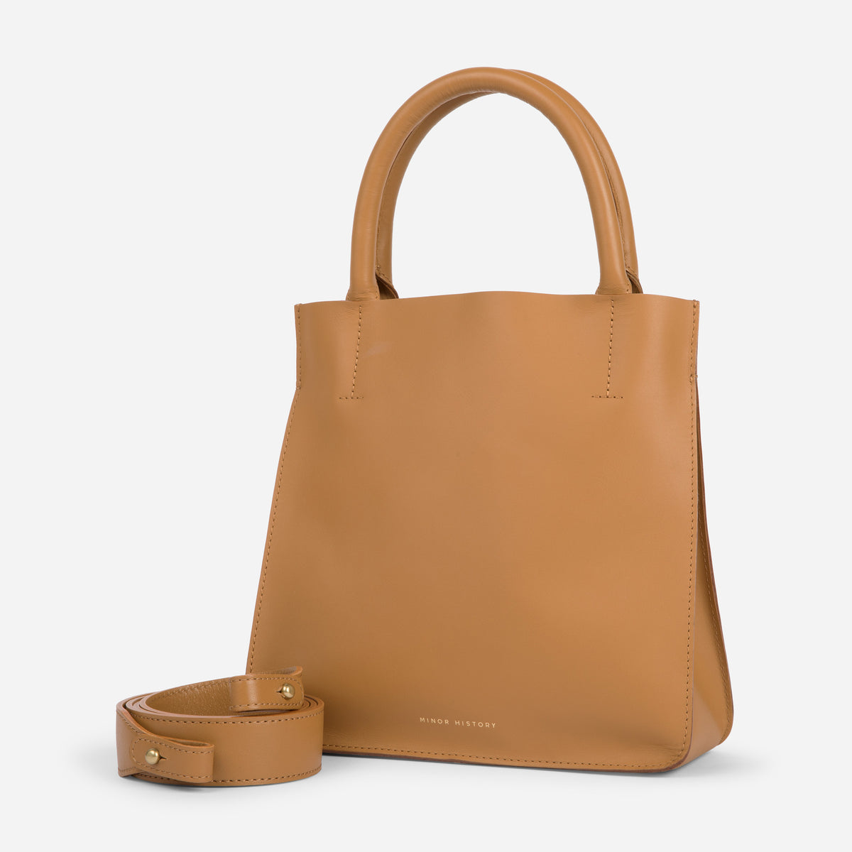 A brown crossbody leather bag with a removable strap and brass hardware, displayed against a plain background. - Saddle