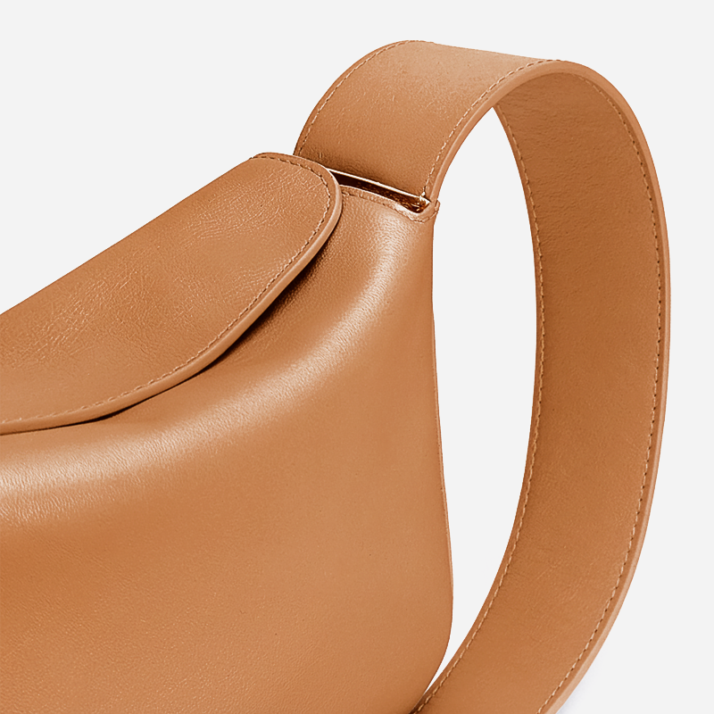 Brown leather handbag with a strap on a light gray background - Saddle