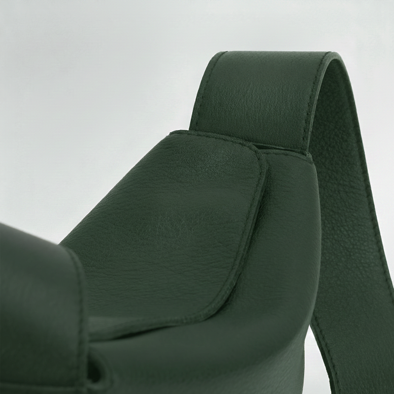 Close-up of a green leather bag with a strap on a light gray background  - Evergreen