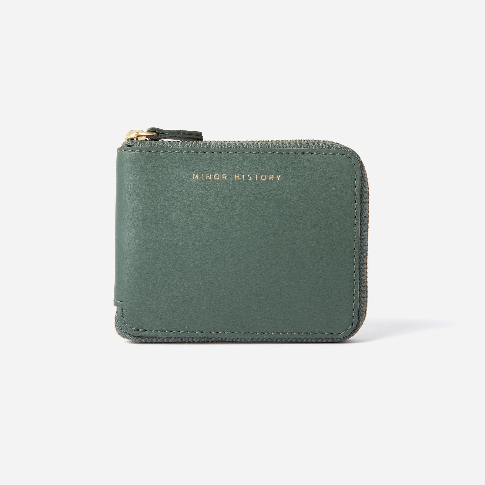 Brown wallet with 'Minor History' branding on a pink fabric background - Saddle