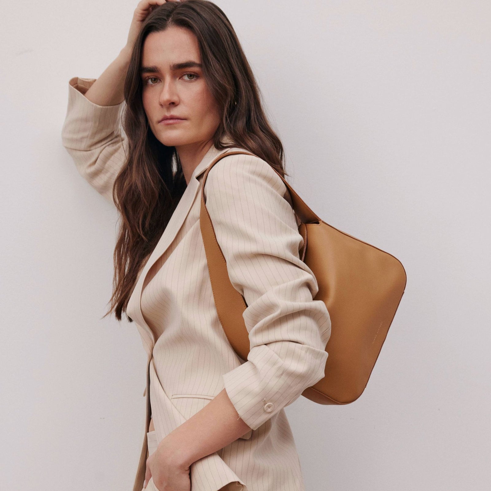 Frame Bag in luxury full-grain leather, minimalist women's handbag in a bright studio setting - Saddle