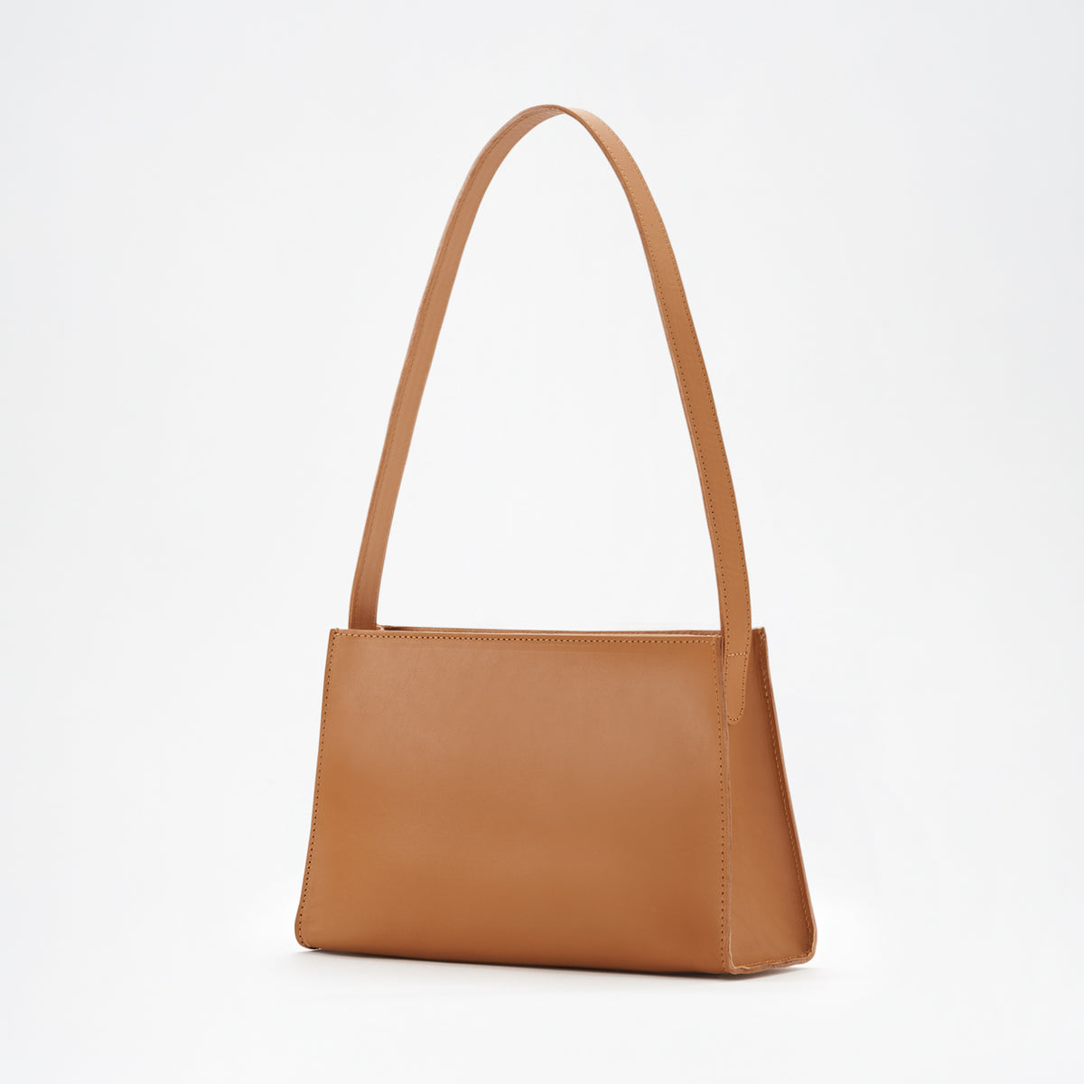 A brown leather shoulder bag with a minimal design, a sturdy zipper, and a delicate shoulder strap, displayed against a white background. - Saddle